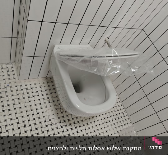 אסלה מותקנת עם צינור חשוף ואריחים לבנים